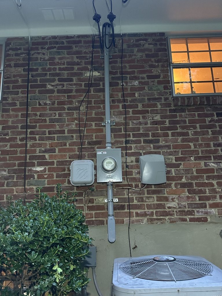 After — upgraded meter and service mast on brick wall
